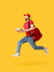 Shocked male courier with pizza boxes jumping on yellow background