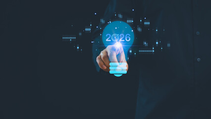 Futuristic business concept showing hand businessman pointing to glowing light bulb with 2026 target, symbolizing innovation, vision, technology trends, and strategic planning for future success.
