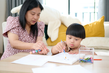 A mother and child spending quality time together, engaged in a creative drawing activity. The mother is attentively assisting her child as they draw on paper with colorful markers
