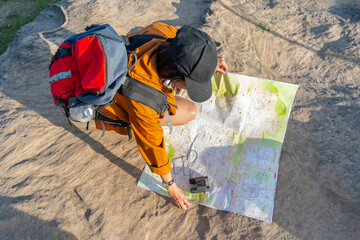 Hiking woman holding a compass. Tourist girl trying to find her way out of the forest using a compass.