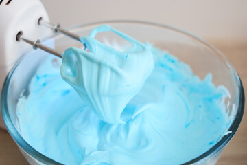 Mixer with whipped blue egg albumen on table in kitchen, closeup