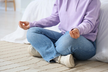 Fototapeta premium Young woman meditating on carpet in bedroom. Zen concept