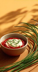 Creamy, red dip in a bowl, topped with chives, bathed in warm light