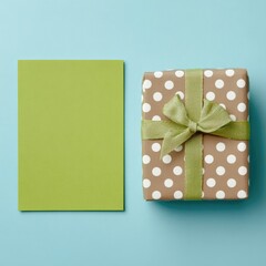 Flat lay of a light-olive-green rectangular card and a light-brown gift box with light-olive ribbon.  The box has a polka dot pattern
