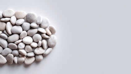 A cluster of smooth, off-white pebbles forms a curved shape against a plain, light gray backdrop