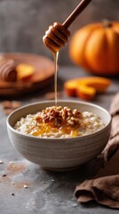 Fototapeta premium A cozy bowl of autumn oatmeal features creamy pumpkin puree, drizzled honey, and crunchy pecans. This inviting breakfast is perfect for chilly mornings in fall