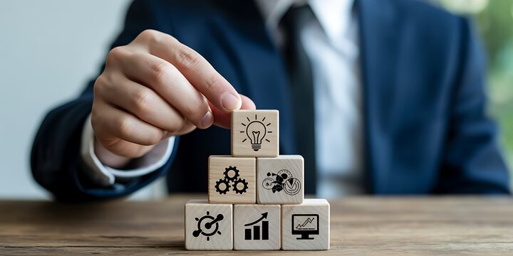 Hand placing a light bulb block on top of business strategy blocks