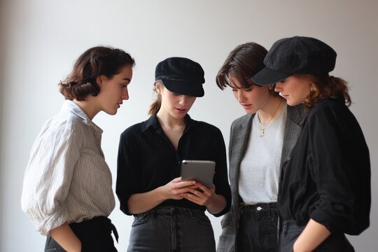 Group of young women looking at tablet together in casual indoor setting.