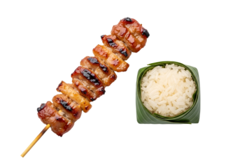 Grilled pork skewers and rice in a banana leaf, a delicious Asian food presentation against a dark background.
