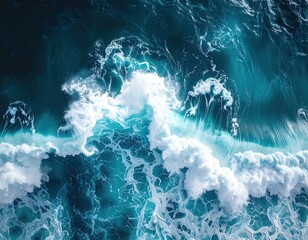 Aerial shot of powerful ocean waves crashing, creating white foam patterns and swirling textures on deep blue and turquoise waters