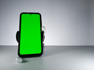Picture of a smartphone showing green screen with earphones attached. This photo is taken with white background. This photo can be used for musical theme advertisement or music related promotion
