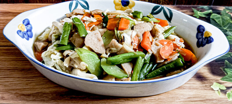 A favorite dish is capcay vegetables mixed with meatballs served in a bowl. A brown background.