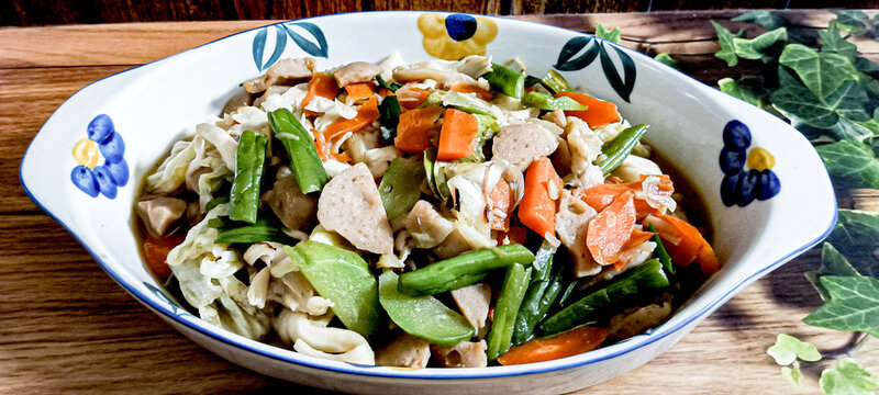 A favorite dish is capcay vegetables mixed with meatballs served in a bowl. A brown background.