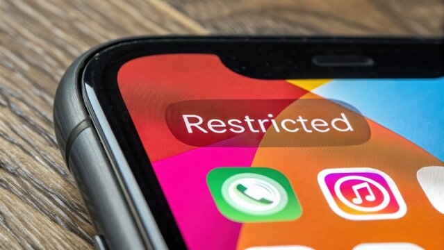 Smartphone screen displays Restricted notification on social media app icon, symbolizing media ban