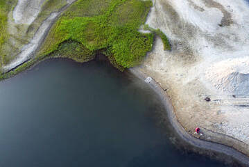 Aerial View Of Green Marsh Wetland Along Shallow Shoreline And Wate