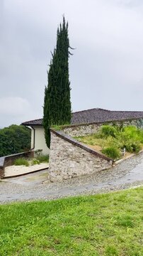 The stone castle features a rectangular shape with a round tower at one corner topped by a conical roof. The stone walkway along the walls has a crenellated parapet for defense. Brescia, Italy