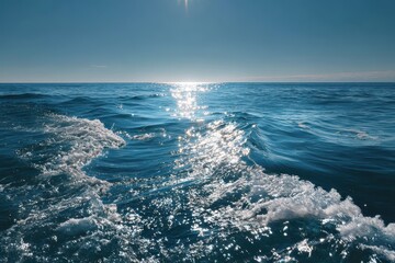 Obraz premium Serene ocean waves gently roll on deep blue water under the bright sun, creating a tranquil atmosphere perfect for relaxation and reflection near the horizon