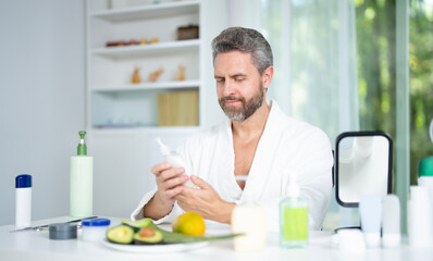 Male beauty facial treatment for healthy skin. Handsome male using beauty cosmetic products to enhance facial beauty. Man practicing facial care for a beauty routine. Aged male skin concept.