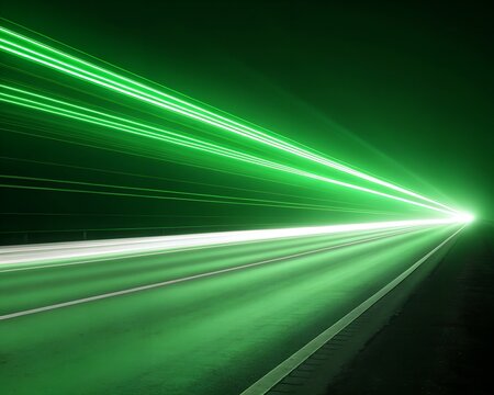 Abstract green light trails streaking across a dark road, representing speed and motion