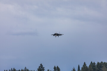 A powerful American twin-engine fighter jet flying in the sky during an air show event, demonstrating military aviation speed, agility, and maneuverability against the clouds, captured in Oregon, USA