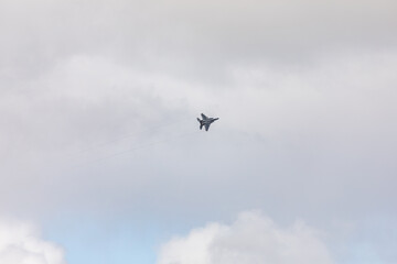 A powerful American twin-engine fighter jet flying in the sky during an air show event, demonstrating military aviation speed, agility, and maneuverability against the clouds, captured in Oregon, USA