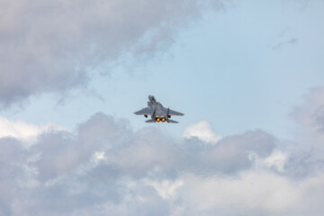 A powerful American twin-engine fighter jet flying in the sky during an air show event, demonstrating military aviation speed, agility, and maneuverability against the clouds, captured in Oregon, USA