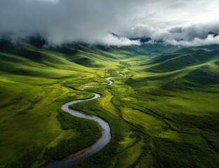 Winding river through lush green valley, mountainous backdrop