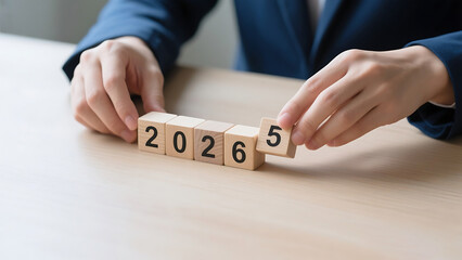 Hands arranging wooden blocks showing the year 2026