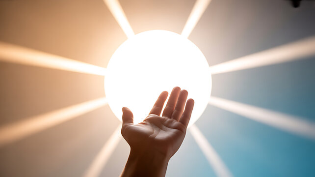 Hand reaching toward a bright light source with radiant beams in a symbolic gesture