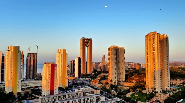 The urban skyline showcases a diverse array of highrise buildings set against the backdrop of clear blue skies