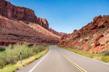 Empty scenic country road with stunning view of eroded red sandstone landscape at both sides in Utah, United States
