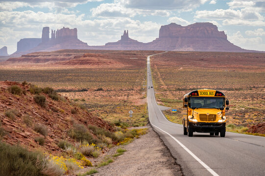 Yellow school bus on US highway route 163 at Forrest Gump Point, a scenic road in Monument Valley and famous filming location in Utah, United States.