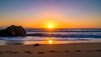 Sunrise paints ocean waves gold, footprints mark sandy shore