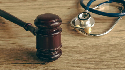 A gavel and stethoscope on a wooden table, symbolizing the intersection of medicine and the law.