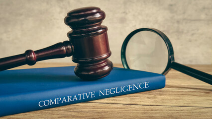 A gavel and magnifying glass on a book titled "COMPARATIVE NEGLIGENCE," symbolizing a legal investigation.