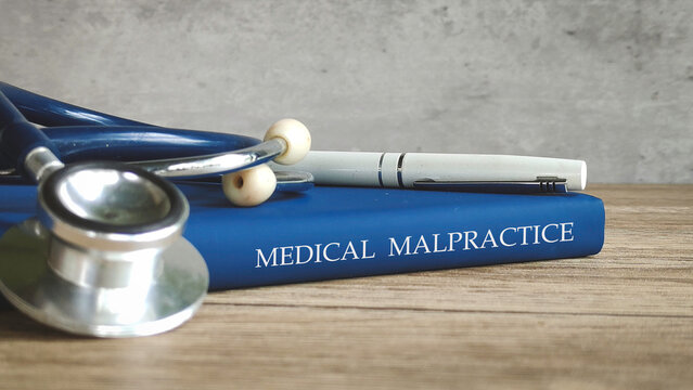 Stethoscope and a pen on a book titled "MEDICAL MALPRACTICE," representing legal issues in healthcare.