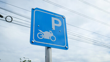 Blue traffic sign with motorcycle icon and letter P indicating designated motorcycle parking area, symbolizing organization, accessibility, convenience, and clarity in urban transportation.