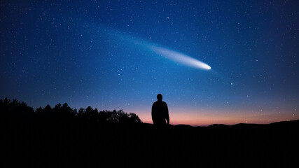 Silhouette of a man and countryside under the stars and comets. © astrosystem