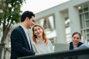 Outdoor meeting showcasing professionals discussing business plans, teamwork, and cultural values in modern organizations. Business or employee group doing work on rooftop restuarant.