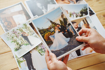 Men's hands put on the wooden table and show wedding photos.