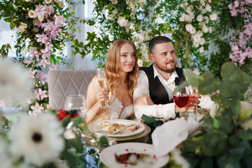 The bride and groom at the newlyweds' table, decorated with many flowers. 