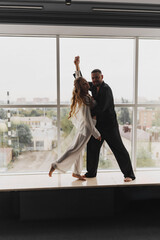 A gentle and romantic man and woman in silk pajamas on the windowsill