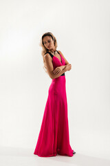 Elegant model poses in a vibrant pink gown against a simple white background