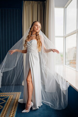 The bride standing by the window. simple beautiful elegant wedding dress