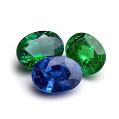 Fototapeta premium Three oval-cut gemstones; two vibrant green, one deep blue, arranged on a white background