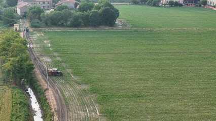 Vast agricultural landscape seen from above showcasing a farmer in a tractor applying chemicals to...