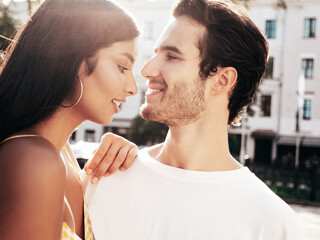 Smiling beautiful woman and her handsome boyfriend. Happy cheerful family. Sexy couple posing in the street at sunrise. During romantic date at sunny summer day outdoors. Looking at each other