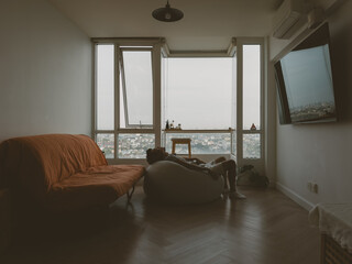 Bright modern living room with orange sofa and city view through large windows
