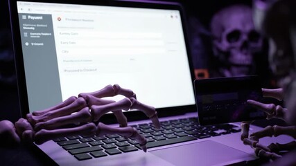 Skeleton hand typing on laptop for Halloween online shopping with festive autumn decor on screen, spooky digital commerce footage. - Powered by Adobe
