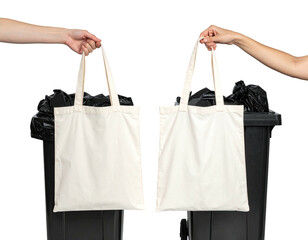 Two hands hold blank canvas tote bags, facing away from a black trash can
